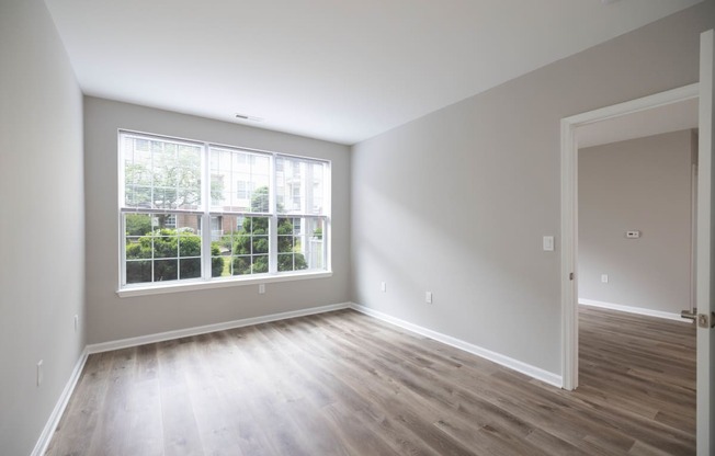 an empty room with wood floors and a large window