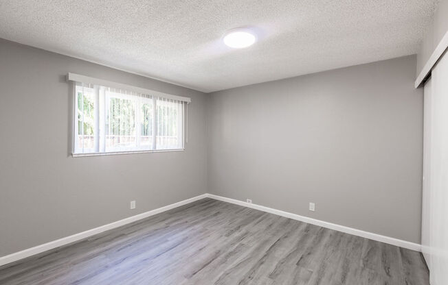 an empty living room with wood floors and a window