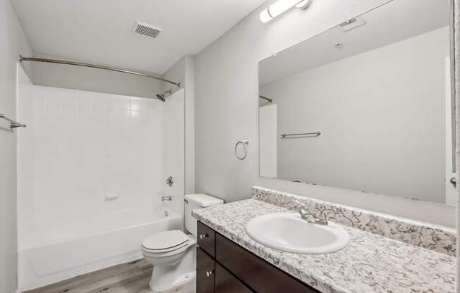 A white bathroom with a toilet, sink, and mirror.