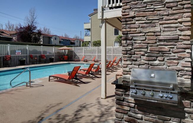 a swimming pool with chairs and a grill on the side of the resident clubhouse at 2000 Lake Washington Apartments, Renton, WA