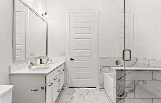 A white bathroom with a marble tub and a white door.