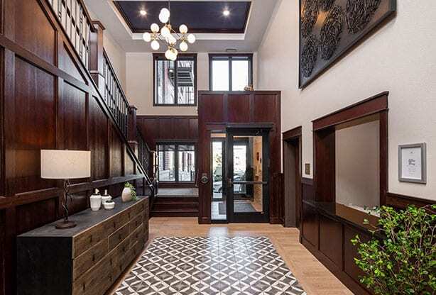 A hallway with a black and white tiled floor and a wooden staircase.
