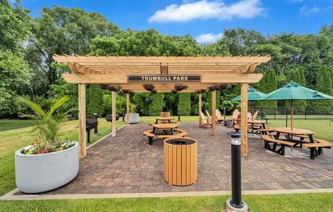a wooden pergola with benches and tables in a park