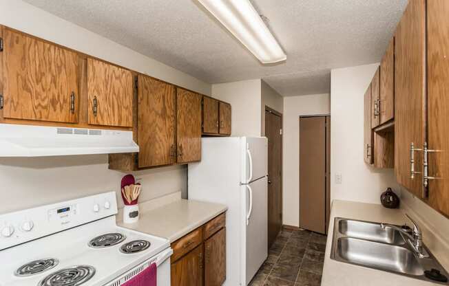 Grand Forks, ND Library Lane Apartments. A kitchen with a white refrigerator freezer next to a stove top oven