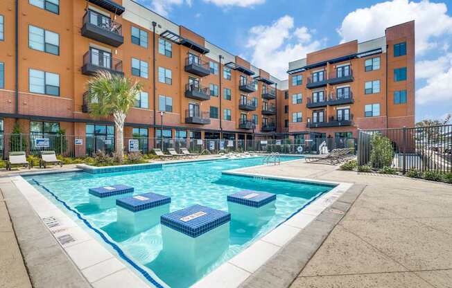 A large swimming pool in front of apartment buildings.