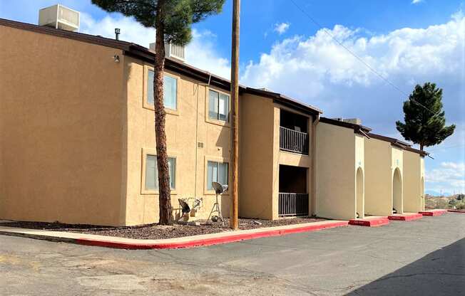A row of apartment buildings with trees in front.