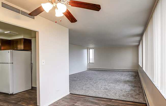 A room with a ceiling fan and a refrigerator.