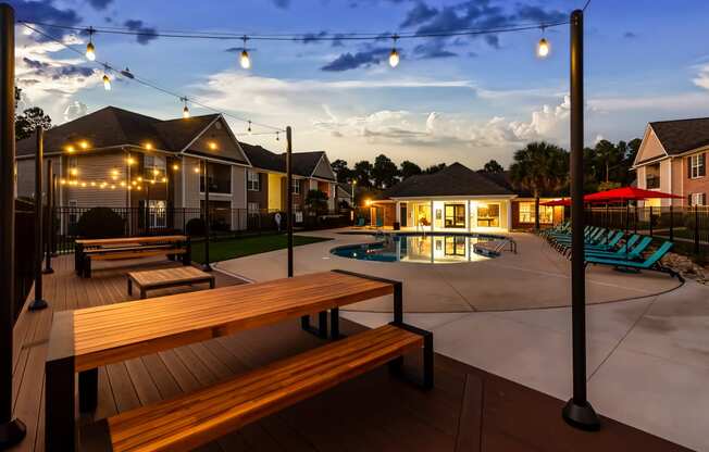 an outdoor patio with benches and a pool at dusk