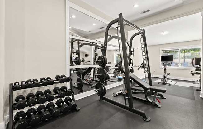 A gym with a variety of equipment including dumbbells, a bench press, and a squat rack.