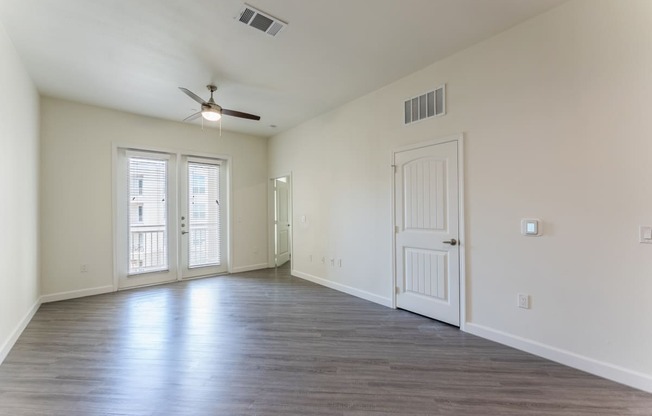 Living room with a ceiling fan and french doors with natural lights at Residences at 3000 Bardin Road, Grand Prairie, TX, 75052