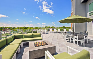 a patio with green couches and chairs and a fire pit