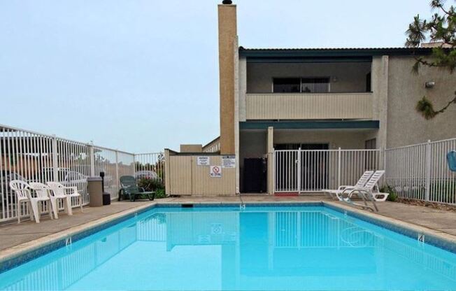 a swimming pool in front of a building with a fence