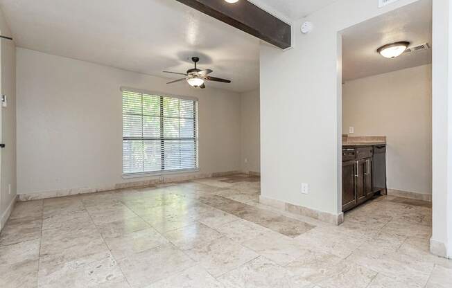 A spacious room with a ceiling fan and a window with blinds.