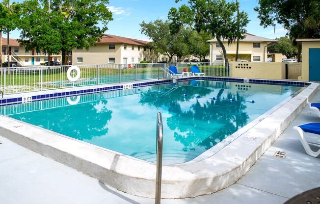 a resort style pool with chairs and a fence around it