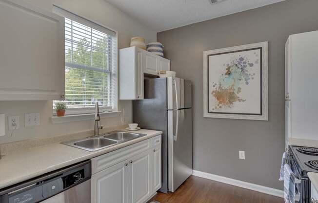 A kitchen with a refrigerator, sink, and cabinets.