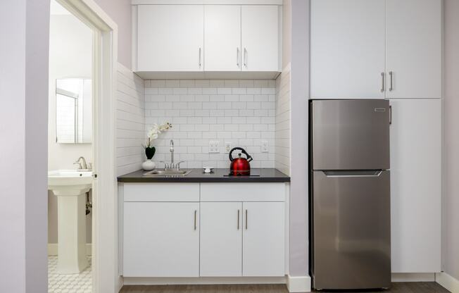 a small kitchen with white cabinets and a stainless steel refrigerator