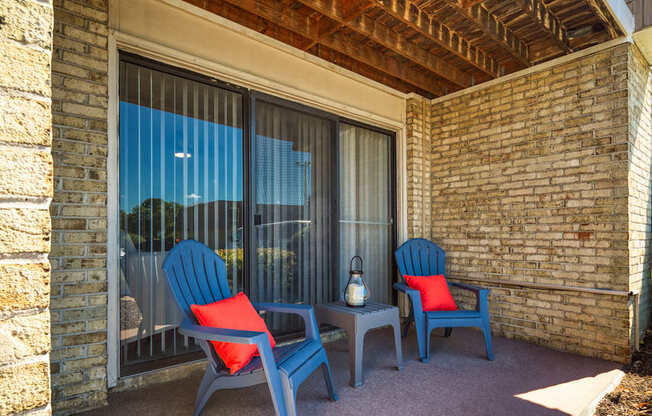 a patio with blue chairs and a table and a window