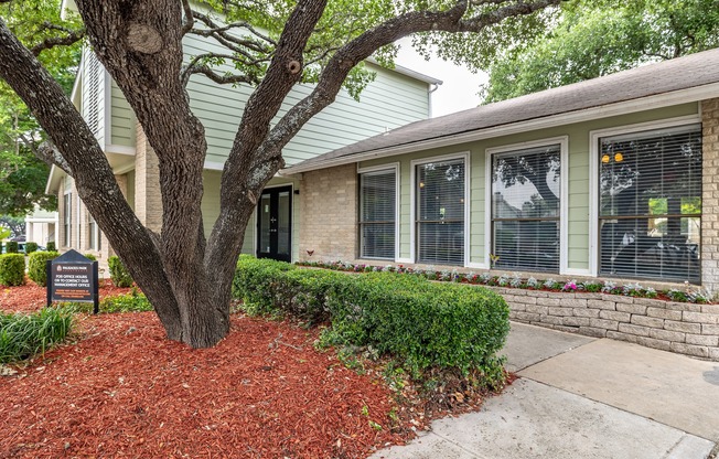 a sidewalk in front of a house with a tree