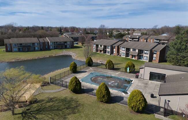 an aerial view of an apartment complex with a swimming pool and a lake