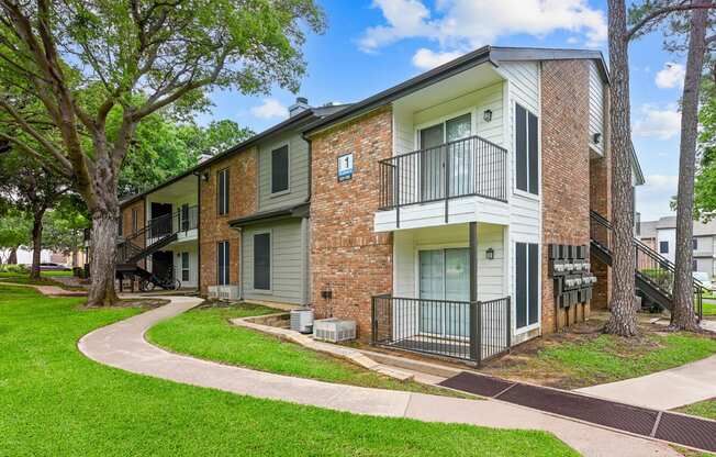 A brick apartment building with a green lawn in front.