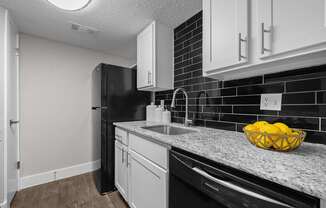 A kitchen with black appliances and white cabinets.