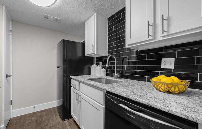 A kitchen with black appliances and white cabinets.