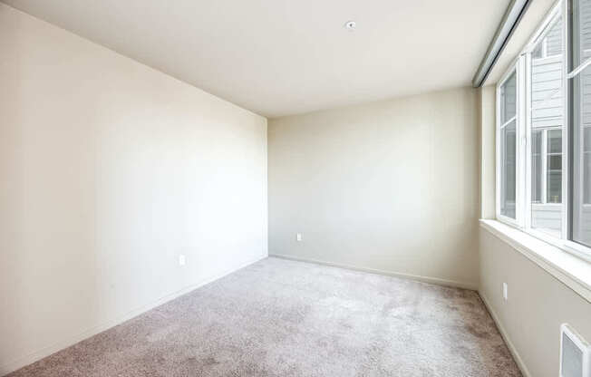 A room with a carpeted floor and a window on the right side.