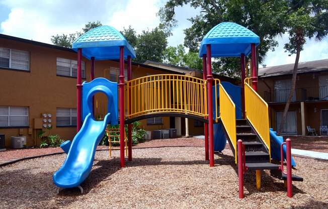 a playground with two slides and a staircase in front of a building