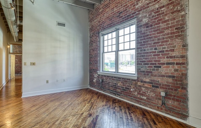 an empty room with a brick wall and a window