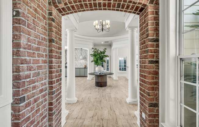 a brick archway leading into a dining room with white pillars and a wood floor