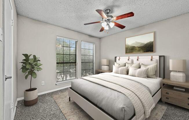 a bedroom with a bed and a ceiling fan at Legacy Apartments in Plano, TX