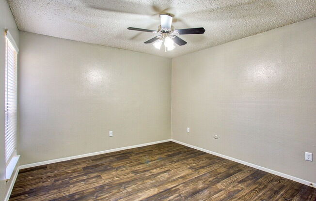 an empty living room with a ceiling fan and wood flooring