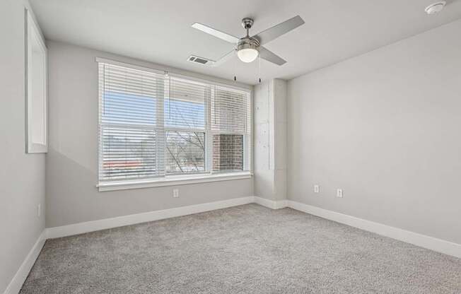 A large bedroom with a ceiling fan and a window s. a large, high ceiling, apartment that has two floors, is a modern loft, and in atlanta