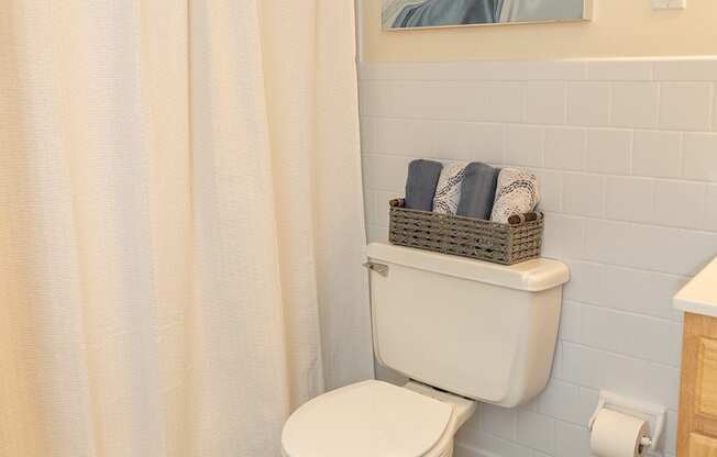 A white toilet in a bathroom with a shower curtain.