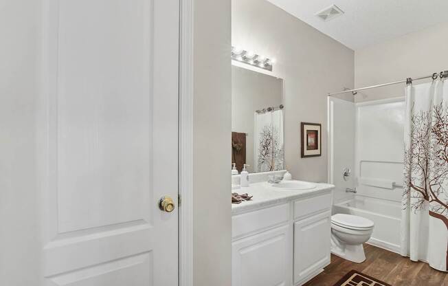 A white bathroom with a toilet, sink, and mirror.
