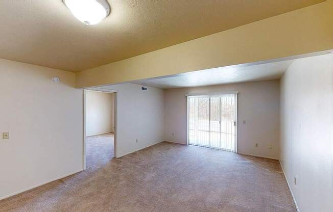 A living room with a slider to a patio and plush carpet at Foxwood and The Hermitage, Portage, MI