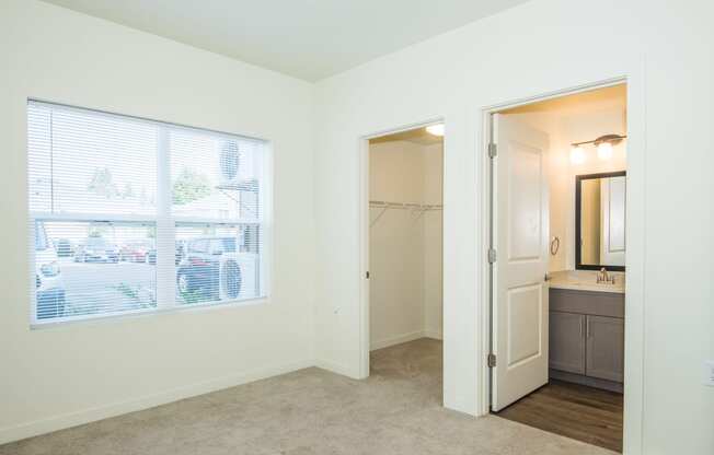 a bedroom with a large window and a door to a bathroom