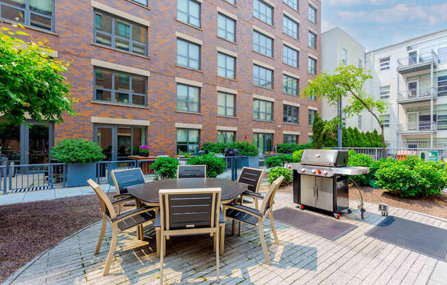 A patio with a table and chairs is surrounded by a brick building.