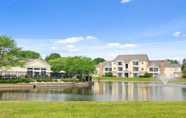 Scenic view of Center Point Apartments with lake, fountain, and clubhouse surrounded by lush landscaping under a clear blue sky.