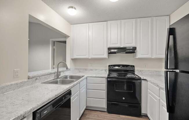 A kitchen with white cabinets and black appliances.