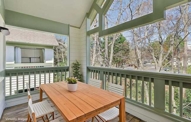 A wooden table with two chairs on a balcony.