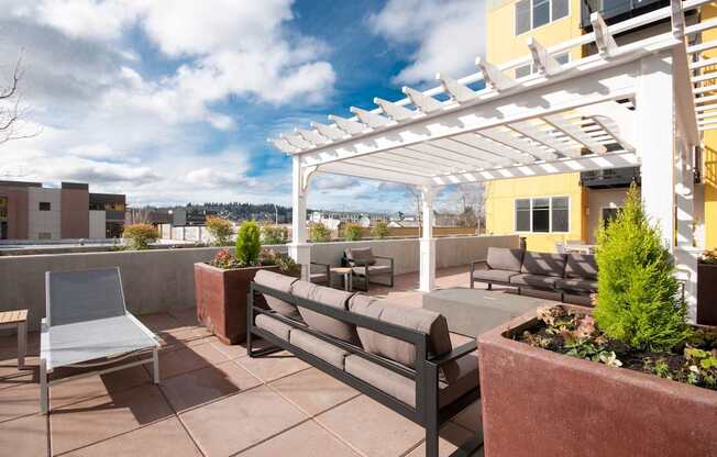 A patio with a white pergola and a bench.