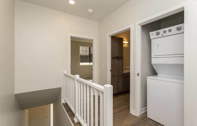 A white kitchen with a stove top oven and a white railing.