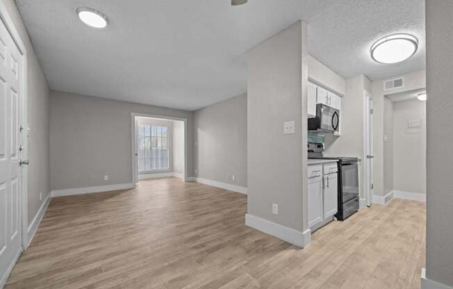 A spacious kitchen with wooden flooring and white walls.