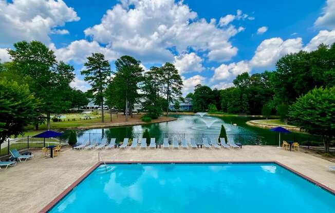 a swimming pool with chairs around it next to a pond