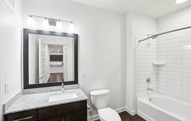 A bathroom with a white tub and shower, sink, and toilet.