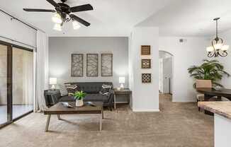 A living room with a black couch and a ceiling fan.