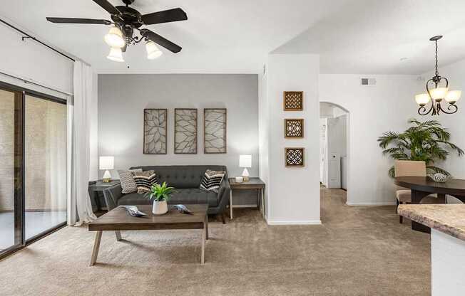 A living room with a black couch and a ceiling fan.