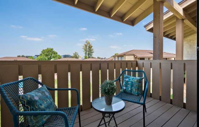 a patio with two chairs and a table on a deck