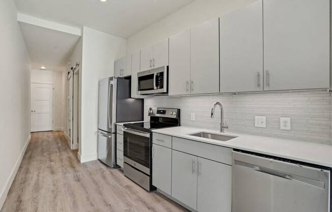 a white kitchen with stainless steel appliances and white cabinets at Sinclaire on Seminary, Alexandria, 22311